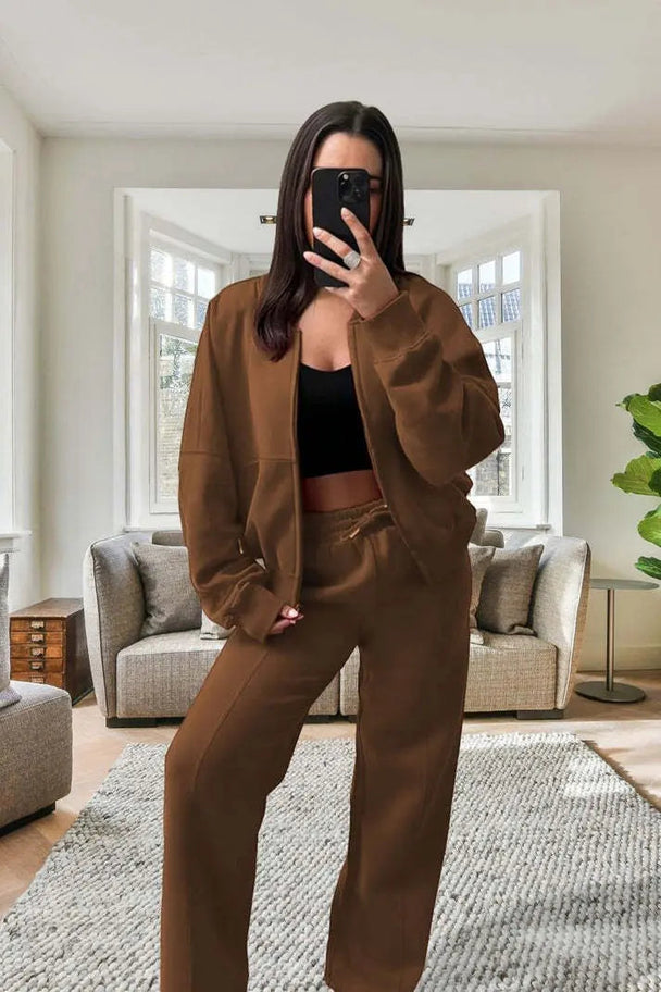 Woman wearing brown oversized fleece bomber tracksuit with zipper jacket and wide-leg pants indoors