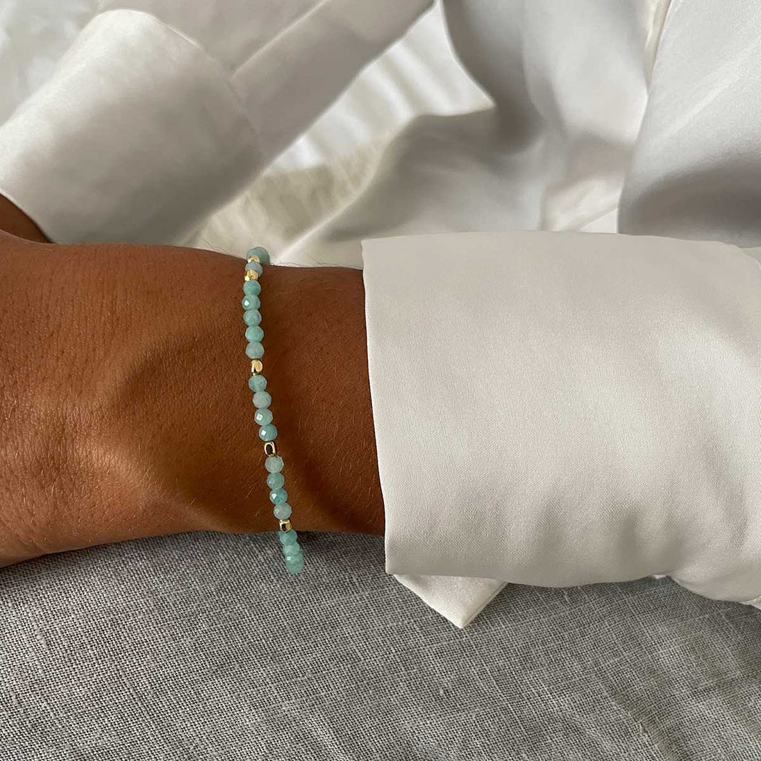 Milos Gemstone amazonite and 22k gold bead bracelet on wrist, adjustable length, luxury pouch included