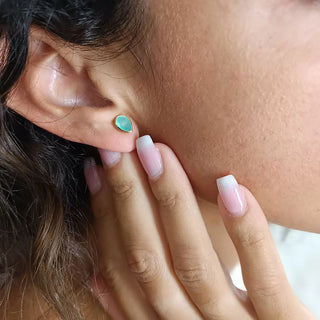 Close-up of a hand wearing Simi Gemstone Studs with teardrop Pariba Onyx set in 22K gold on recycled brass