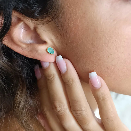 Close-up of a hand wearing Simi Gemstone Studs with teardrop Pariba Onyx set in 22K gold on recycled brass