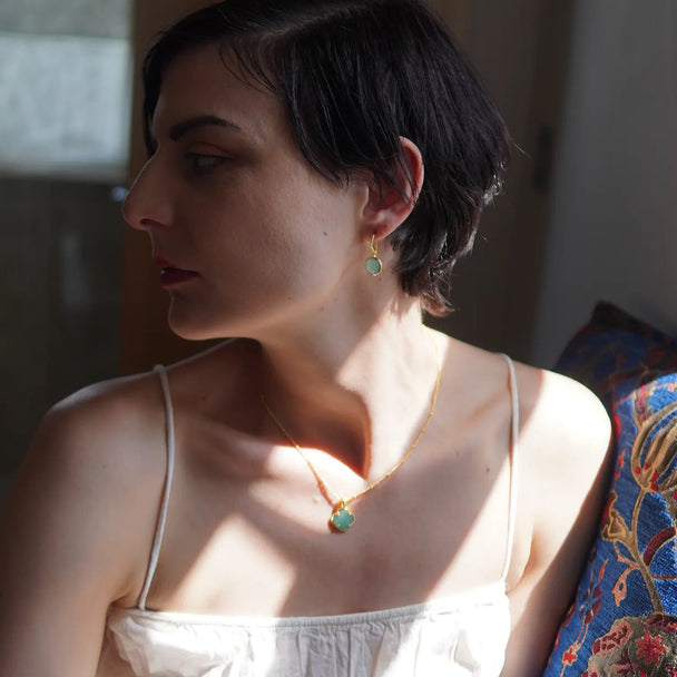 Charis Round Gemstone Earrings featuring Pariba Onyx set in 22 Karat gold on recycled brass worn by woman in soft natural light