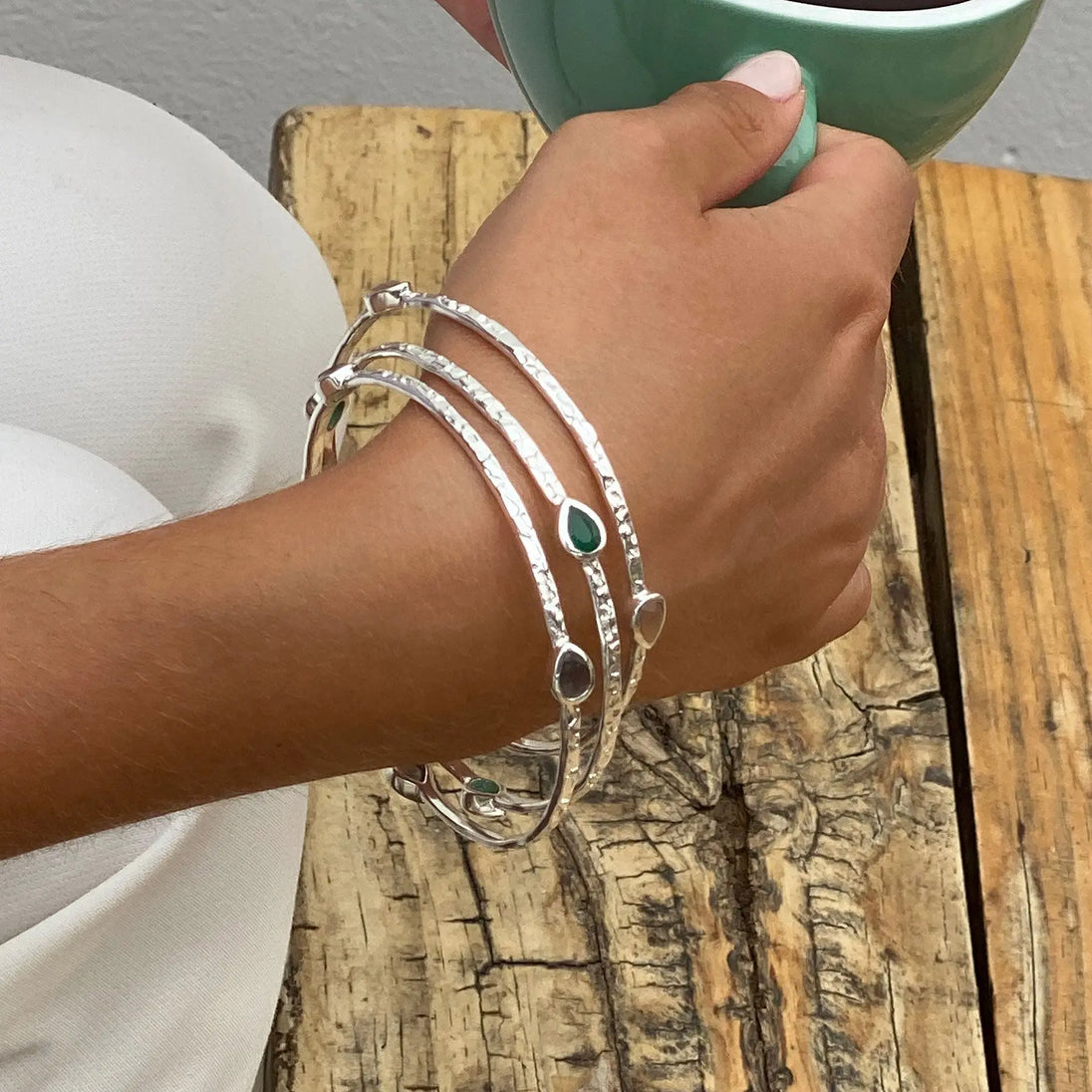 Simi Three Stone Stacking Bangle in sterling silver with Pariba Onyx gemstones on wrist holding green cup