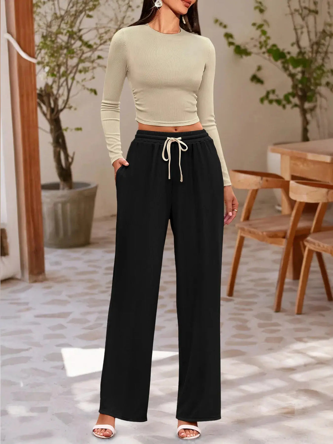 woman wearing round neck long sleeve top and black drawstring pants set in modern indoor setting