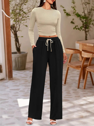 woman wearing round neck long sleeve top and black drawstring pants set in modern indoor setting