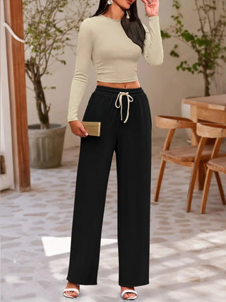 Woman wearing a beige round neck long sleeve top with black drawstring pants set for casual comfort and style