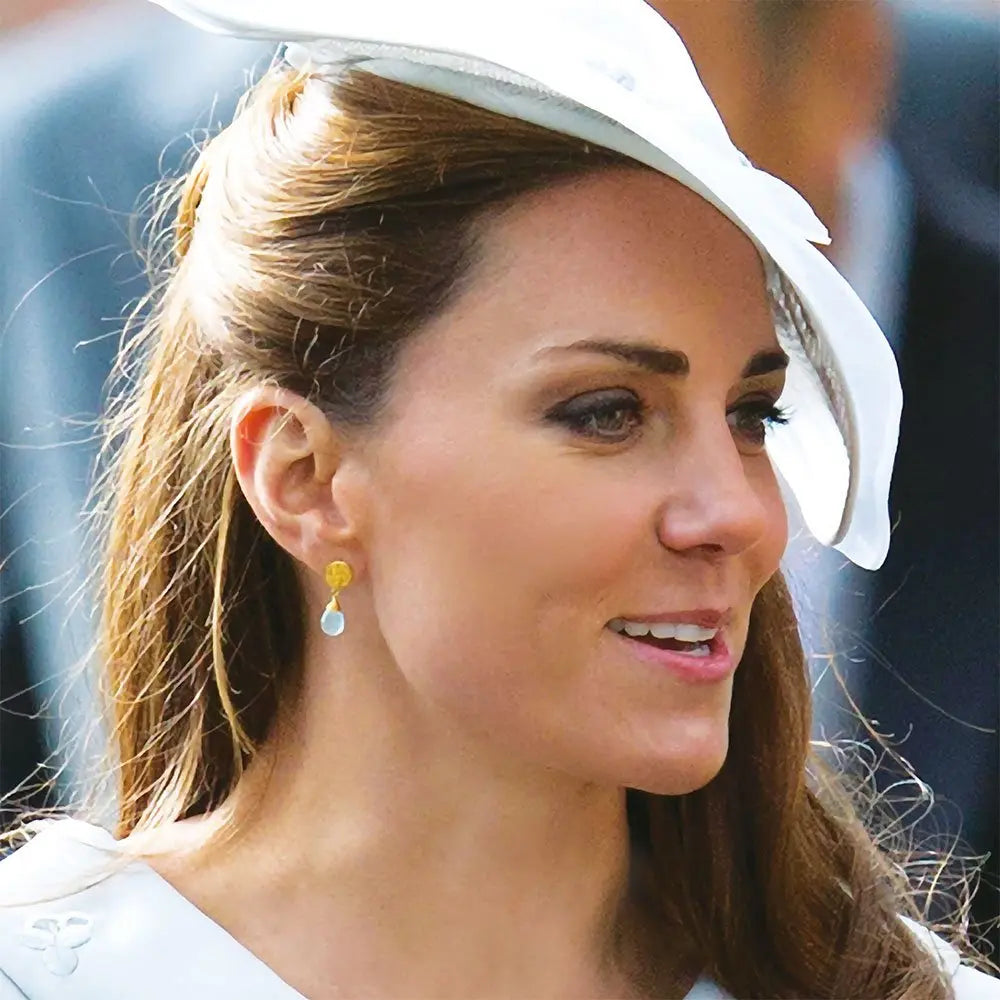 Classic Athena Drop Earrings with white moonstone and 22k gold plated coin stud worn by woman in elegant white hat