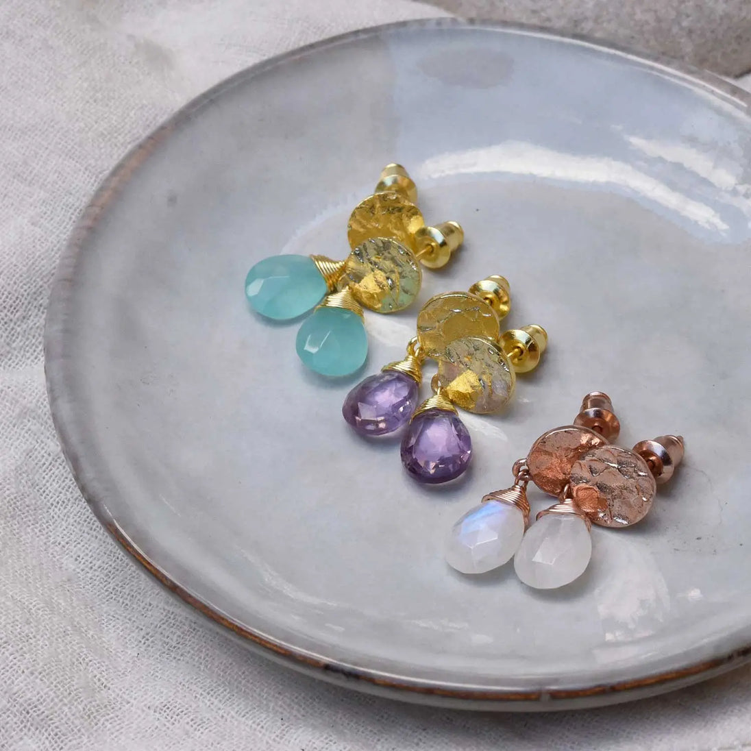 Classic Athena Drop Earrings with rainbow moonstone and 22k gold plated coin studs on a ceramic plate