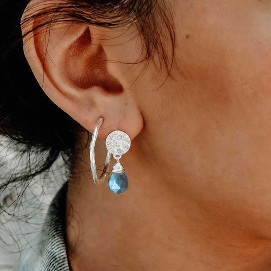 Close-up of ear wearing Classic Athena Drop Earrings with silver textured disc and blue labradorite briolette gemstone drop