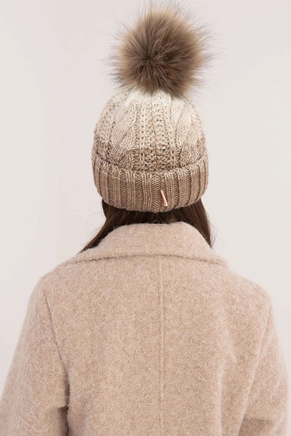 Beige two-tone winter beanie with fluffy pom-pom and fleece lining for warmth and style
