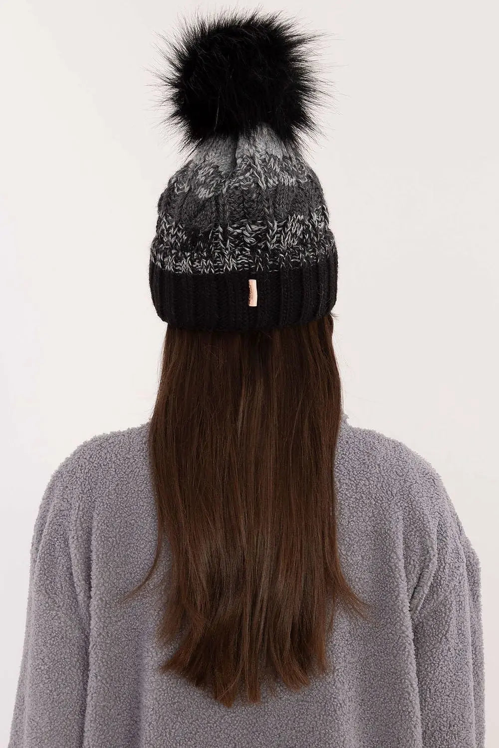 Black and gray two-tone winter beanie with pom-pom and fleece lining on woman