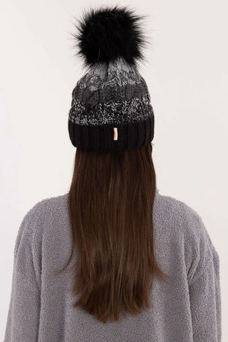 Black and gray two-tone winter beanie with pom-pom and fleece lining on woman