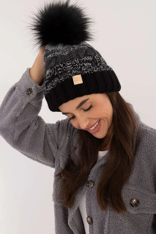 Woman wearing black and gray two-tone winter beanie with pom-pom and plaid pattern