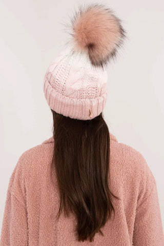 Beige two tone winter beanie with pom-pom and fleece lining on woman wearing pink jacket