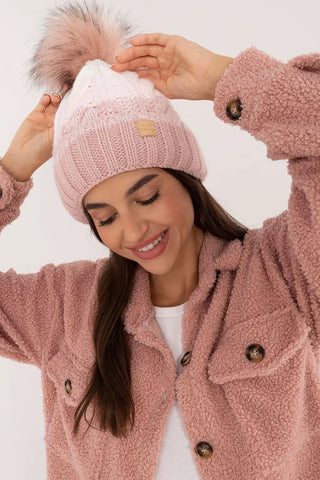 Pink and white two tone winter beanie with fluffy pom-pom and fleece lining worn by smiling woman