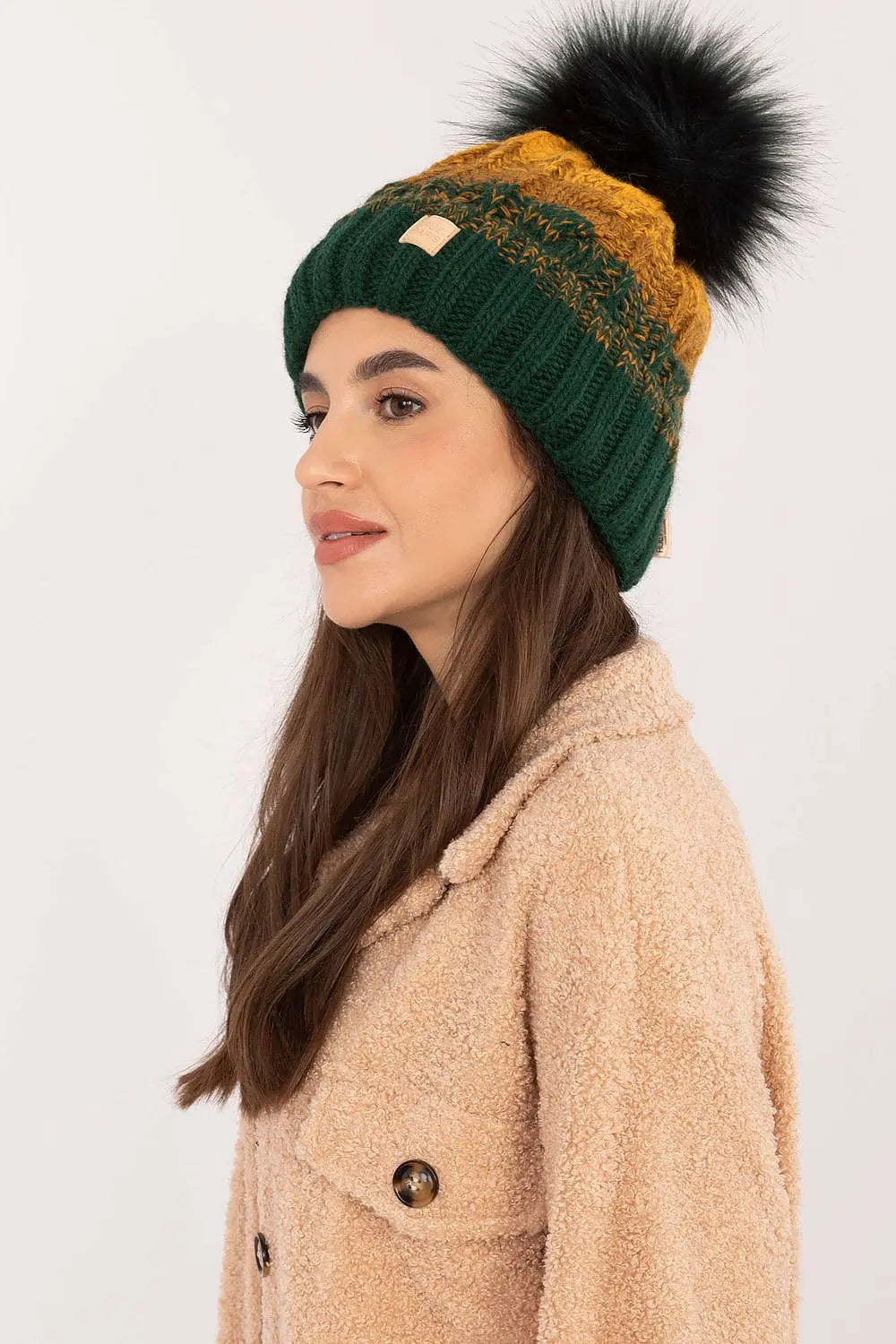 Beige two tone winter beanie with pom-pom and fleece lining on woman in beige coat