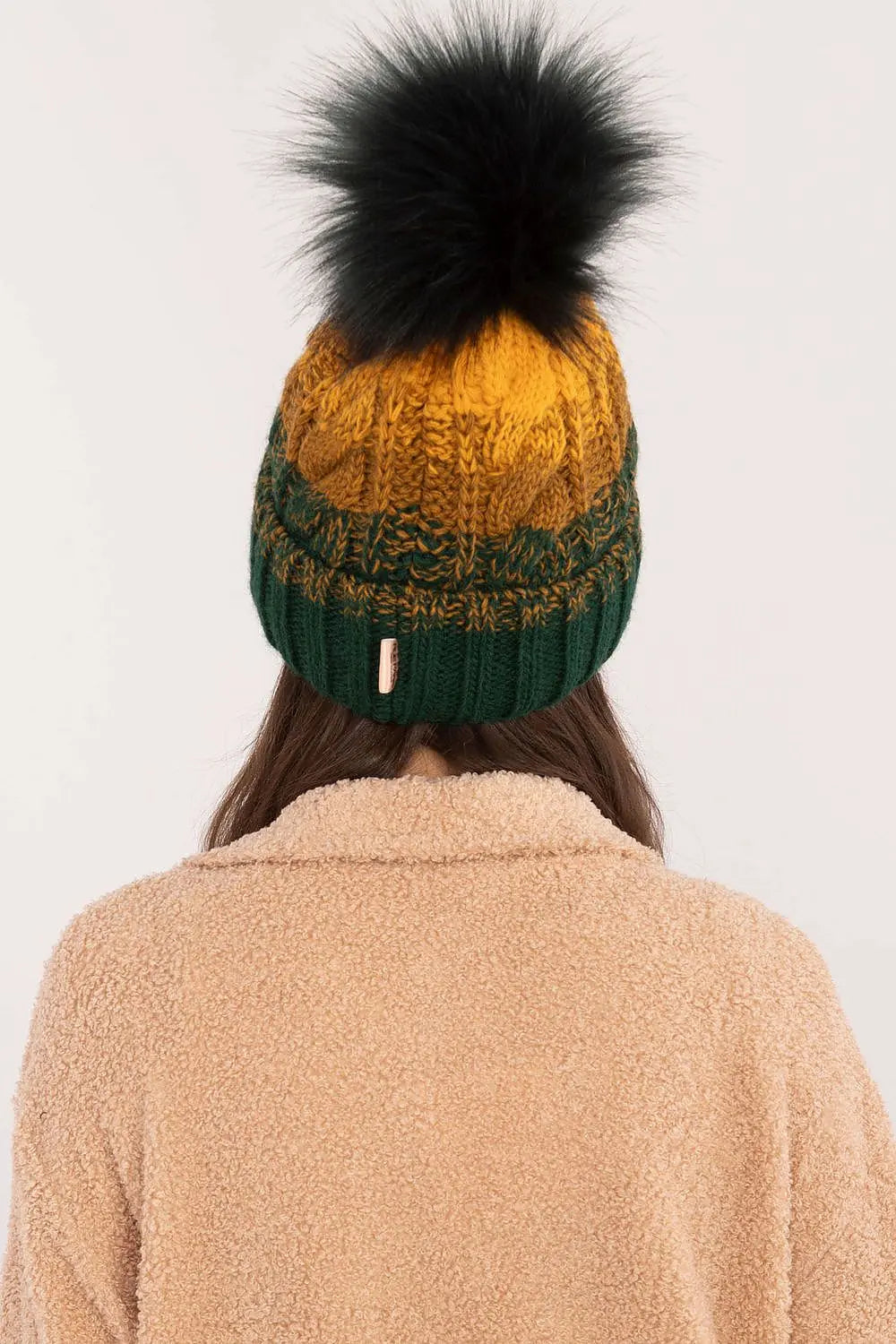 Multicolor knitted winter beanie with large black pom-pom and fleece lining shown from back