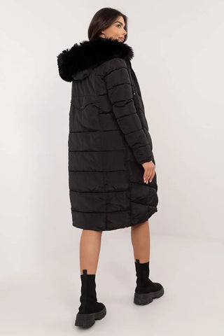 Woman wearing black long quilted down jacket with detachable fur hood and zipper closure