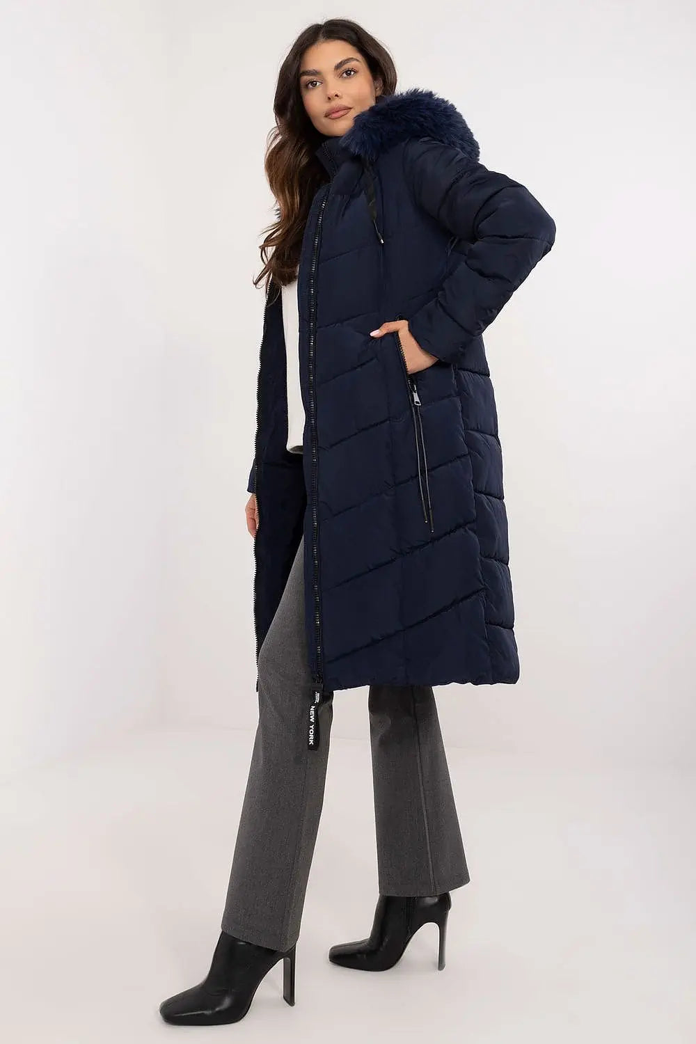 woman wearing navy long quilted down jacket with detachable fur hood and zippered pockets
