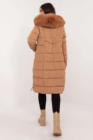 Woman wearing long quilted down jacket with detachable fur hood in camel color, back view.