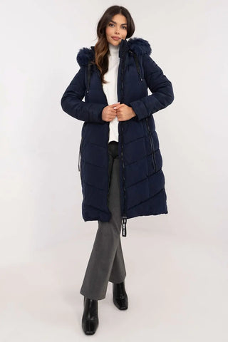 Woman wearing navy long quilted down jacket with detachable fur hood and zipper pockets.