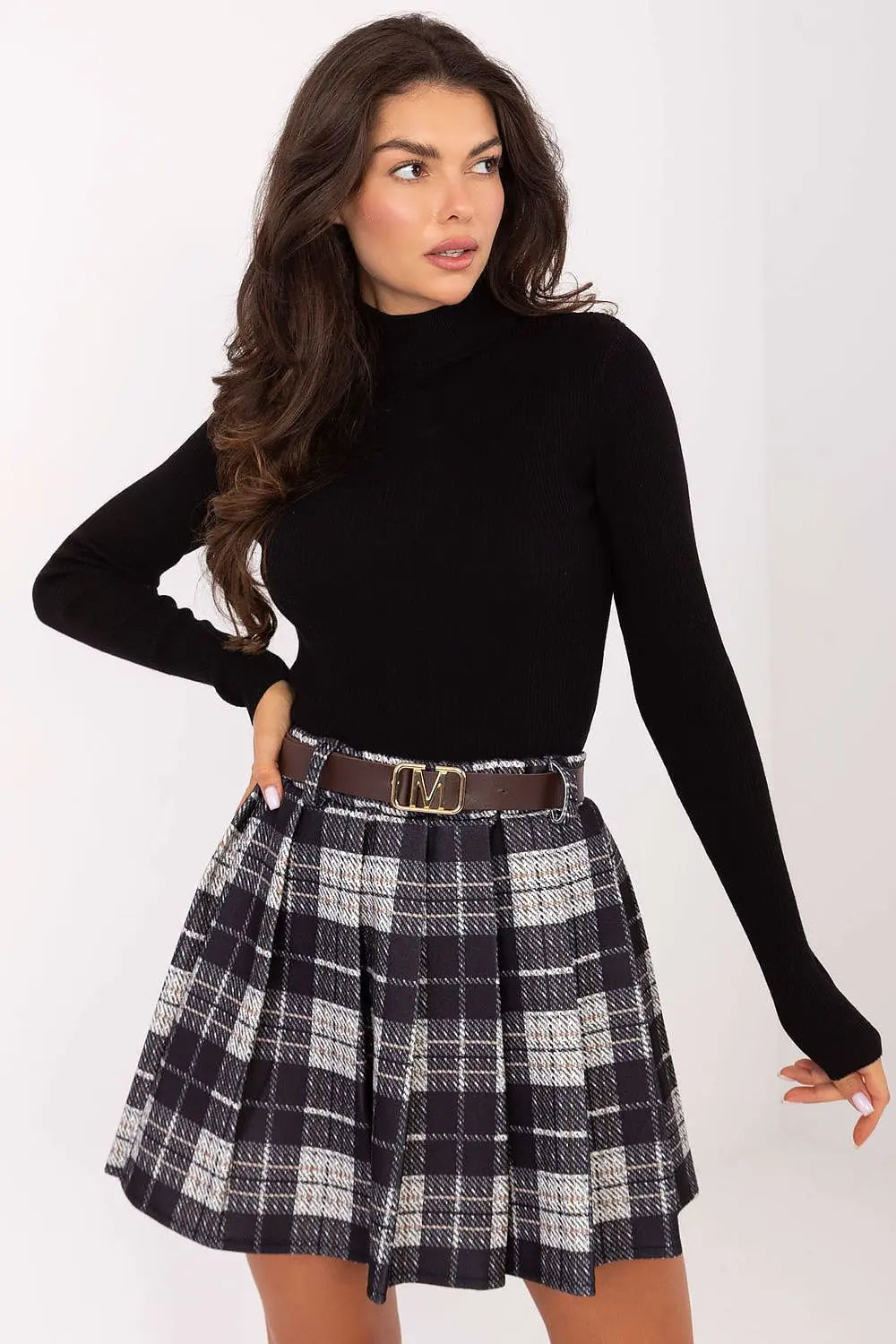 Woman wearing pleated checkered short skirt with belt and black long sleeve top