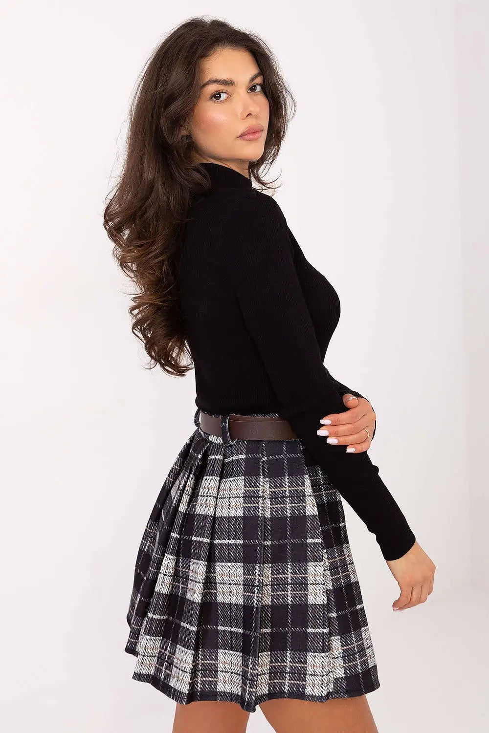 Woman wearing pleated checkered short skirt with belt and black top