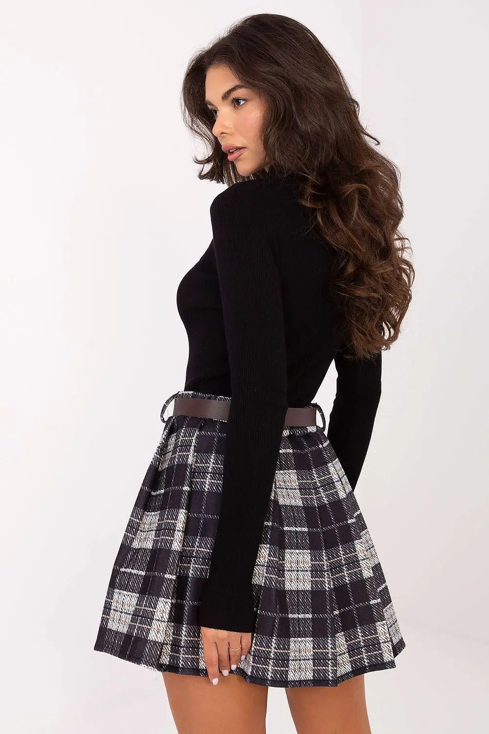 Woman wearing pleated checkered short skirt with elastic waistband and belt on white background