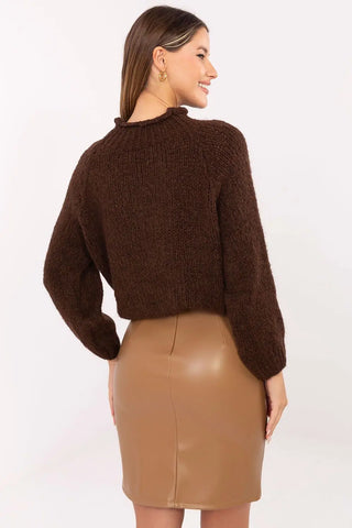 woman wearing brown leather mini skirt and dark brown sweater standing sideways