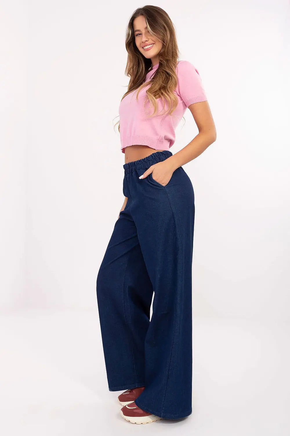 Woman wearing denim wide leg jeans with elastic waist and side pockets, paired with a pink top