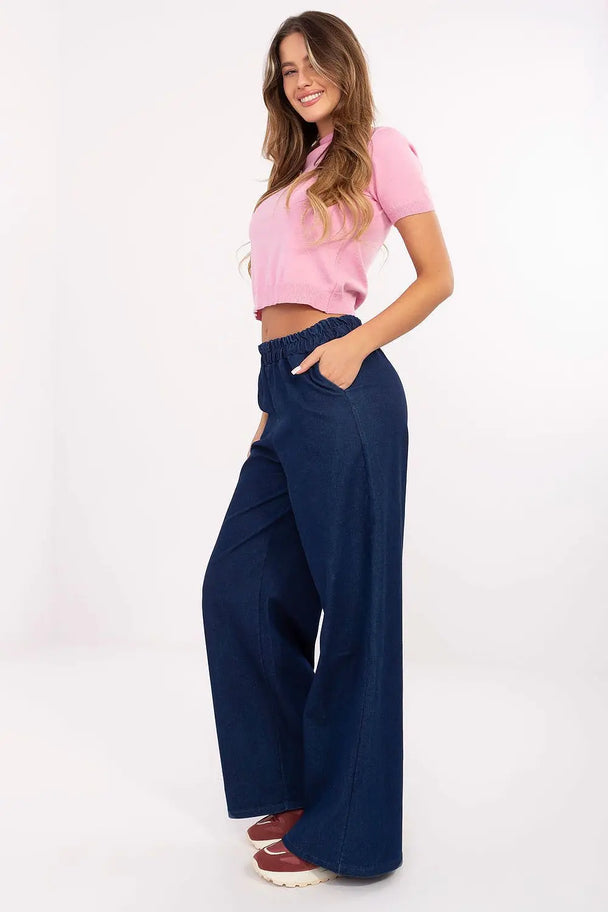 Woman wearing denim wide leg jeans with elastic waist and side pockets, paired with a pink top