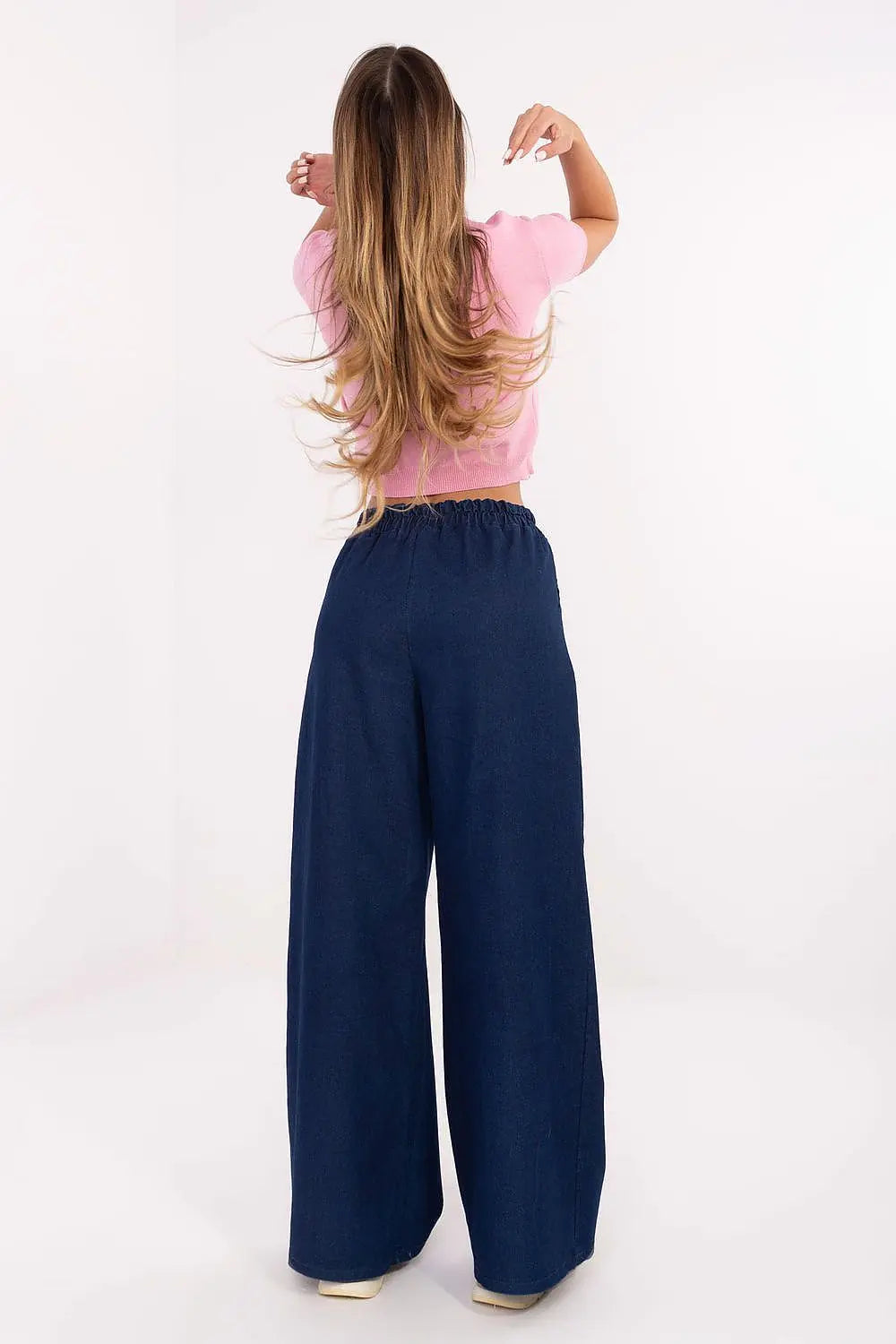 Woman wearing denim wide leg jeans with elastic high waist and casual loose fit, back view