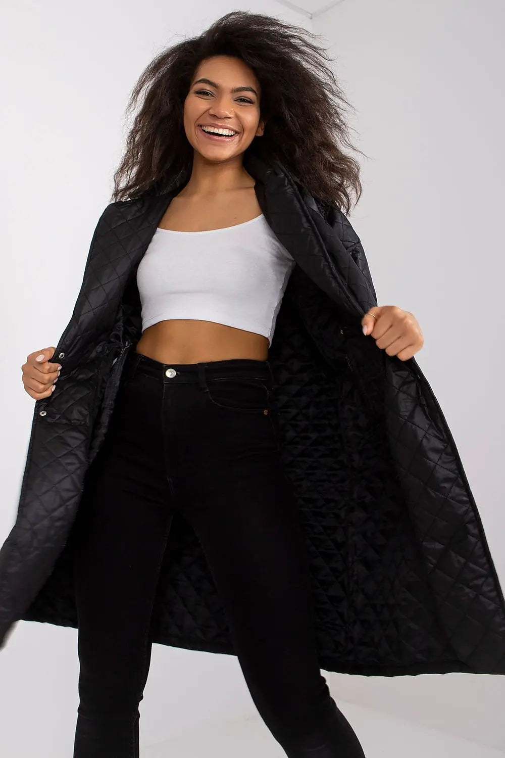 Black quilted women's coat with long sleeves and press stud fastening shown open on smiling model