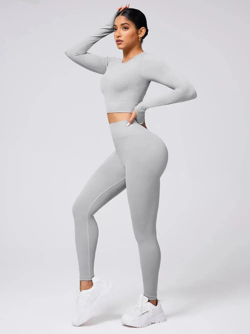 Woman wearing light gray back crisscross long sleeve top and leggings active set with white sneakers
