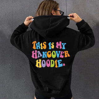 Women’s oversized black hoodie with colorful "THIS IS MY HANGOVER HOODIE" back print, drop shoulder design, and cozy fit