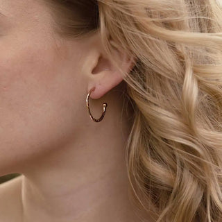Close-up of a woman wearing Lydia Textured Gold Hoops earrings with a handcrafted textured finish, 22mm 22kt gold plated recycled brass hoops