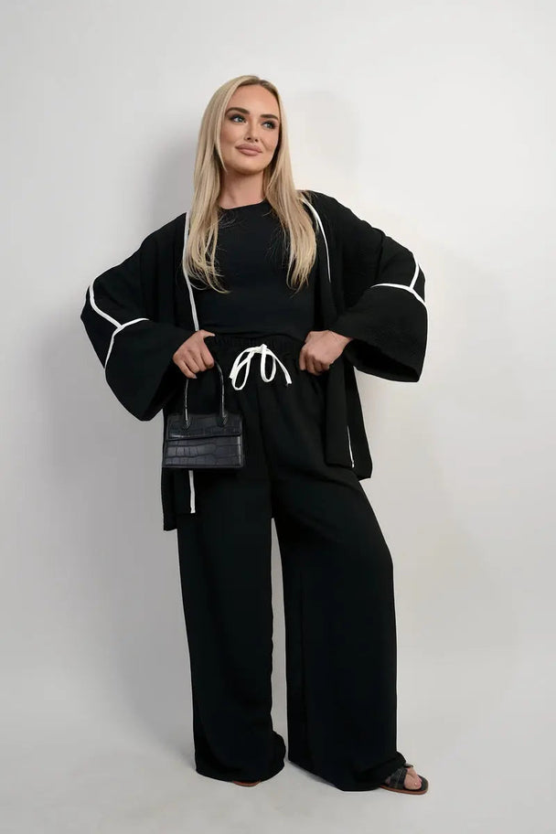 Woman wearing black contrast trim oversized cardigan and wide leg co-ord set with white drawstring pants and black top