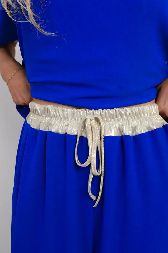 Close-up of shiny waistband drawstring on wide leg blue trousers