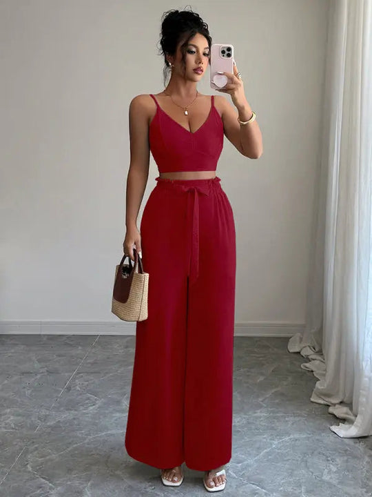 Woman wearing stylish burgundy two-piece set with sleeveless crop top and high-waisted wide-leg pants.